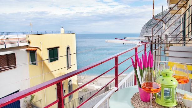 A balcony with a view of the sea, a table with a green lantern, and a pink vase with a plant. - Luigi's room Sorrento (Meta)