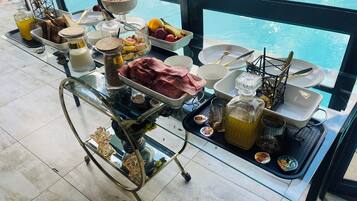 A breakfast trolley with various food items and condiments by a poolside.