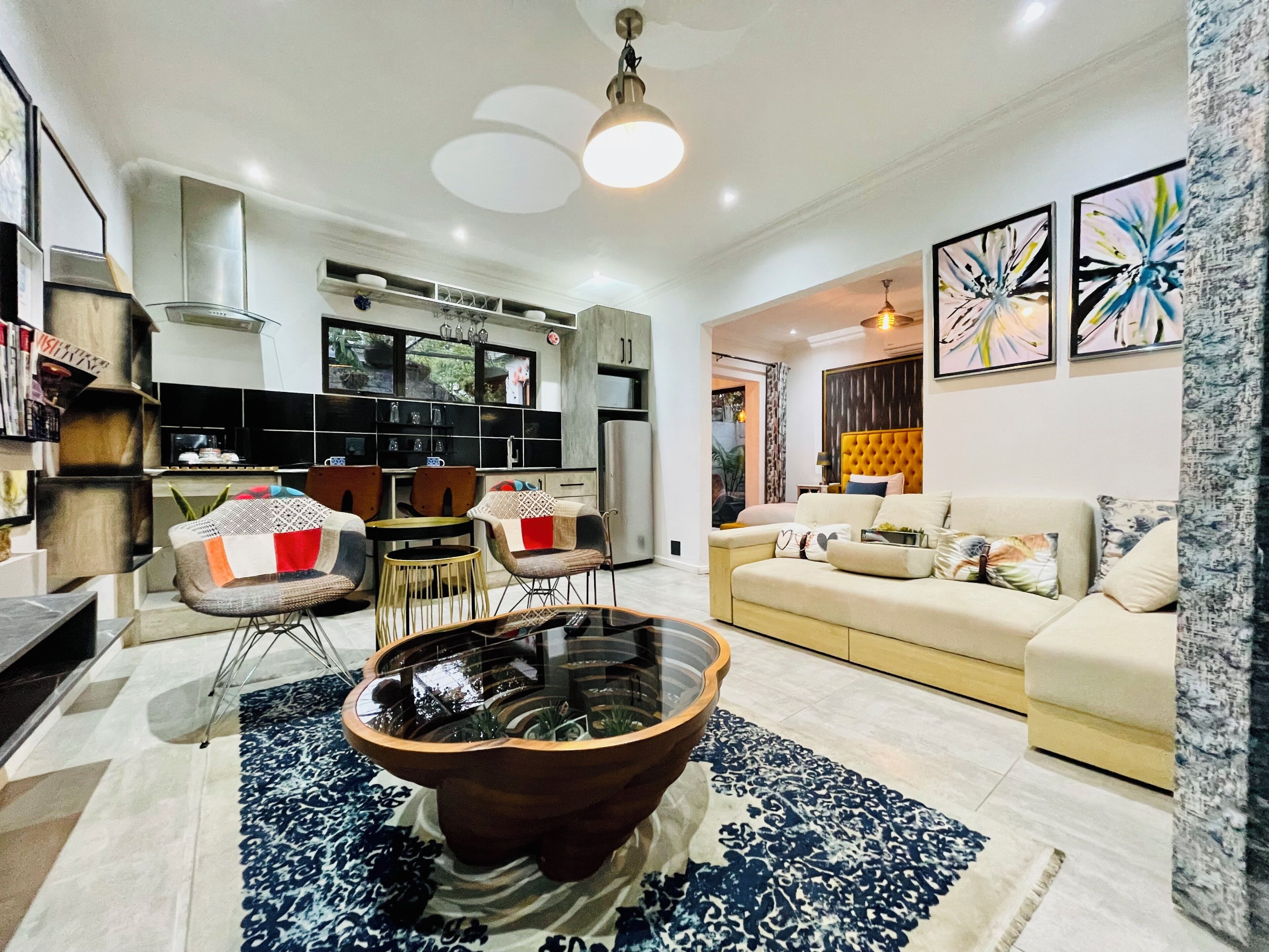 A modern living room with a sofa, armchairs, a coffee table, and a kitchen in the background.
