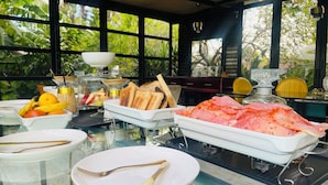 A breakfast buffet with various food items, a glass table, and a view of greenery through large windows. - 24 On Basil Boutique Luxury Hotel (Randburg)