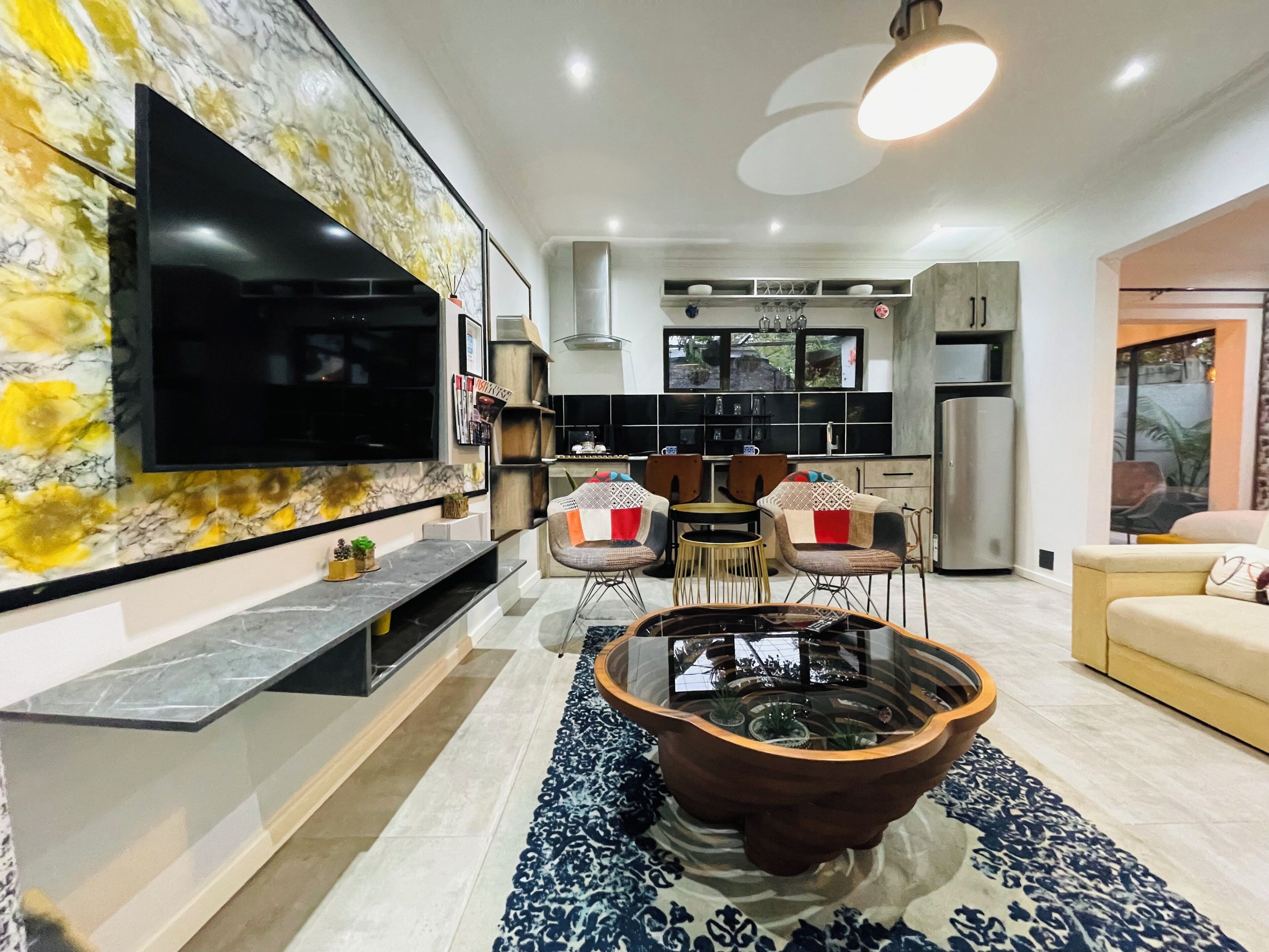 Een moderne woonkamer met een flatscreen televisie, een salontafel en een eethoek met stoelen en een tafel.
