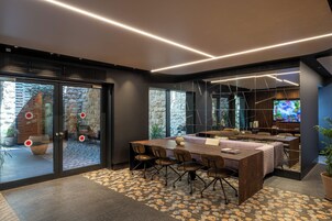 Una sala de conferencias moderna con una mesa grande, sillas y una televisión.