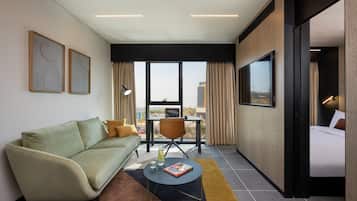 Una habitación de hotel moderna con un sofá, una mesita redonda pequeña, una silla y una cama.