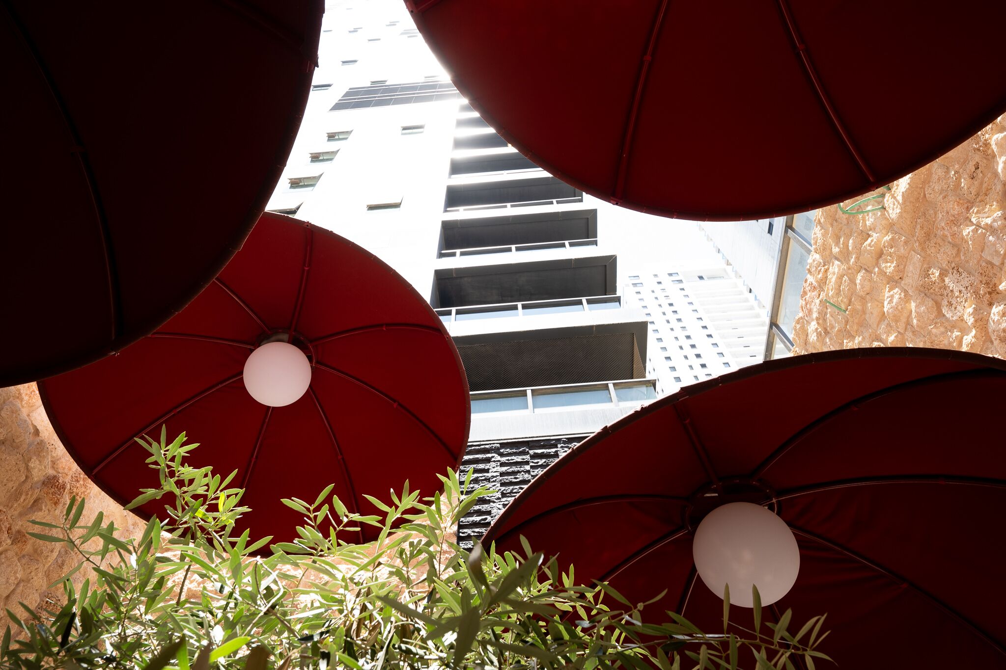 A view of a building with multiple floors and a red umbrella-like structure in the foreground.