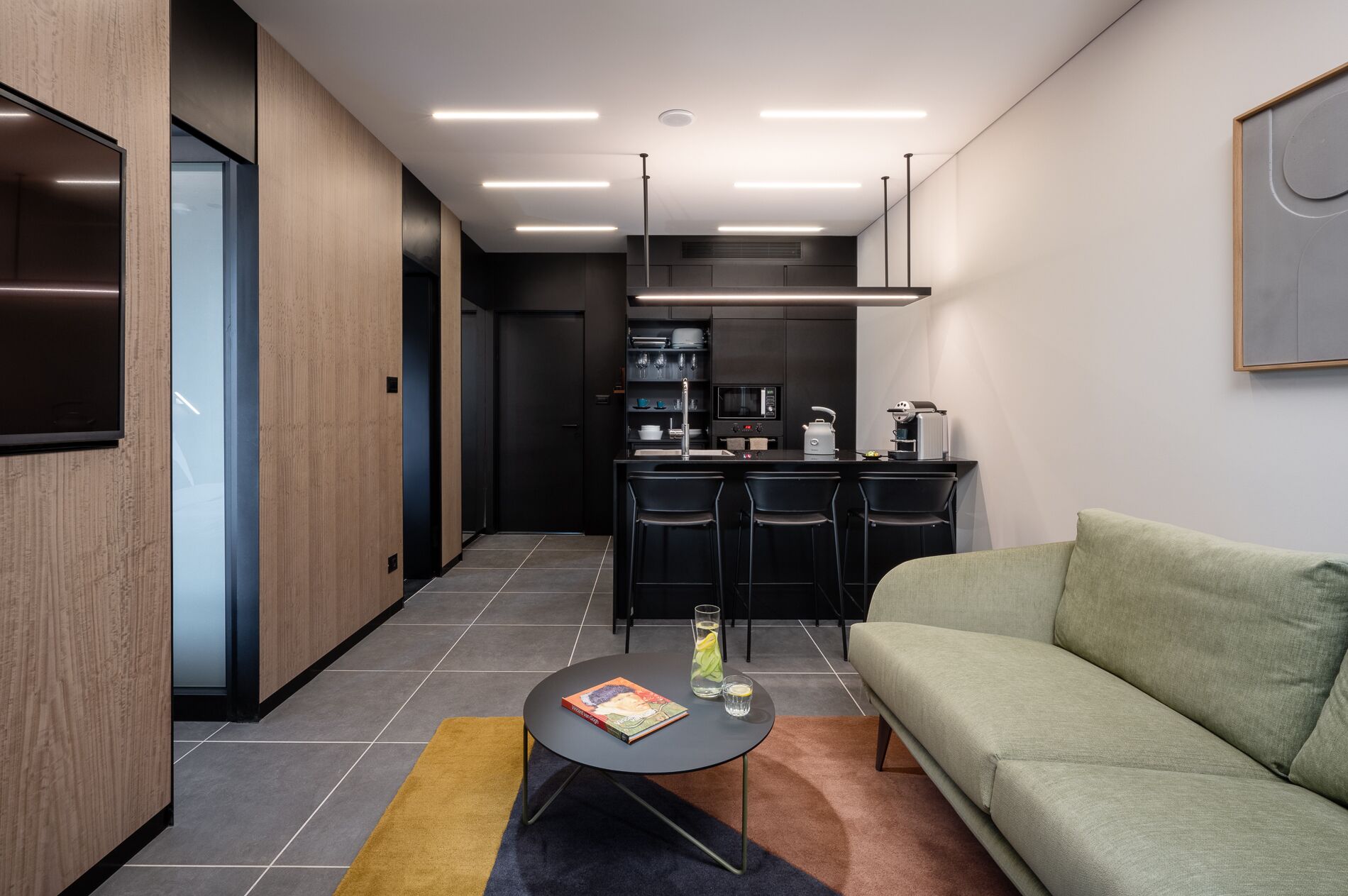 Una sala de estar moderna con sofá, una mesa de centro y una zona de cocina con taburetes de bar.