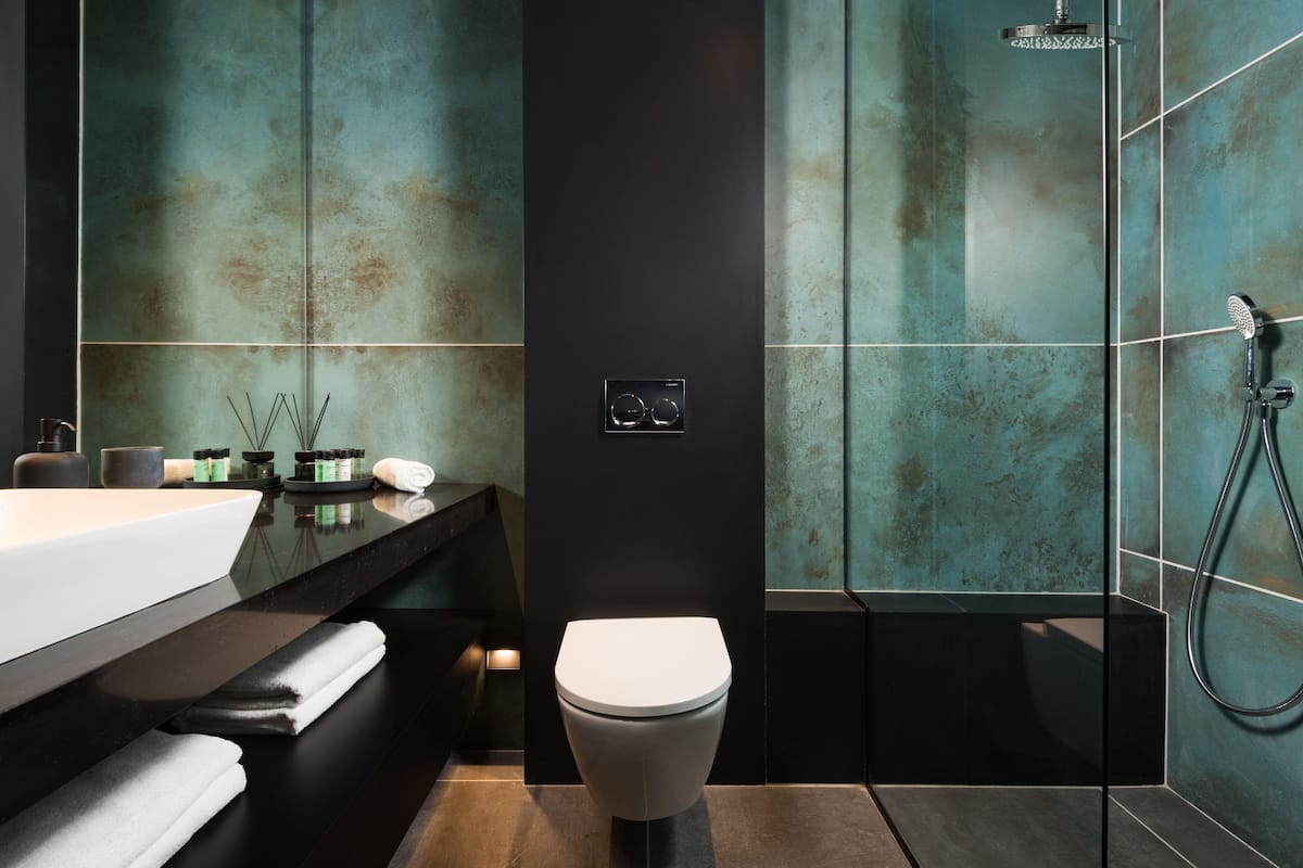 A modern bathroom with a black sink, white toilet, and a glass-enclosed shower area.