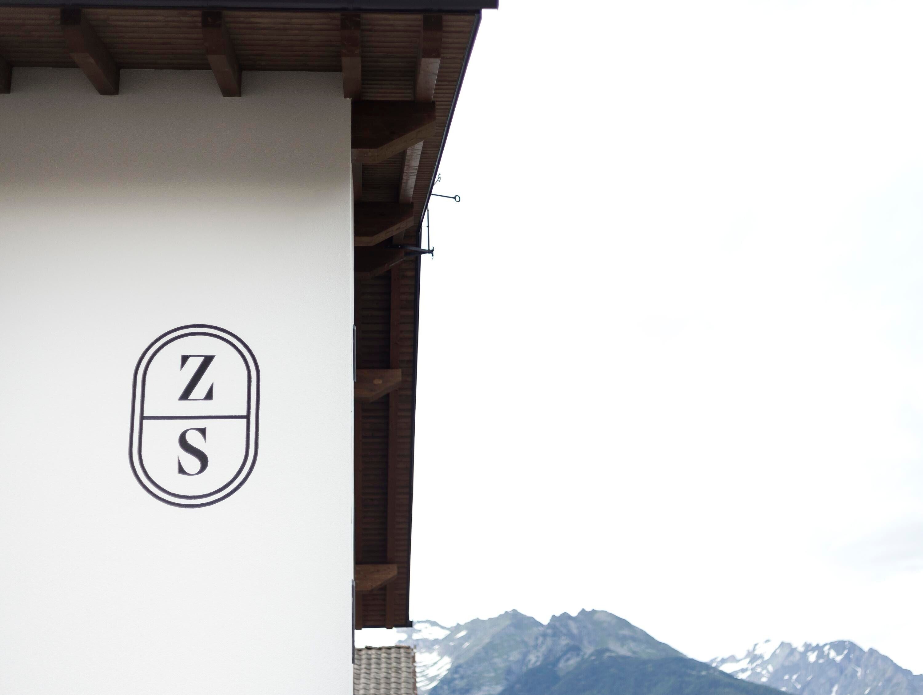 A building with a white exterior and a logo featuring the letters 'Z' and 'S' in a circular design.