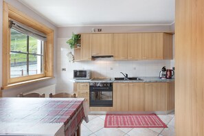 Une cuisine avec des meubles de rangement en bois, un four à micro-ondes, une cuisinière et un évier.