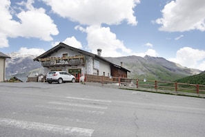 Un immeuble doté d’un balcon, d’une enseigne et d’une voiture garée devant.