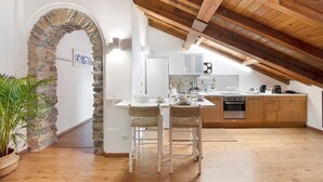 Una cocina con un arco de piedra, vigas de madera en el techo y una encimera blanca.