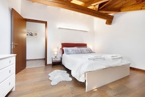 A bedroom with a bed, bedside table, lamp, and a door.