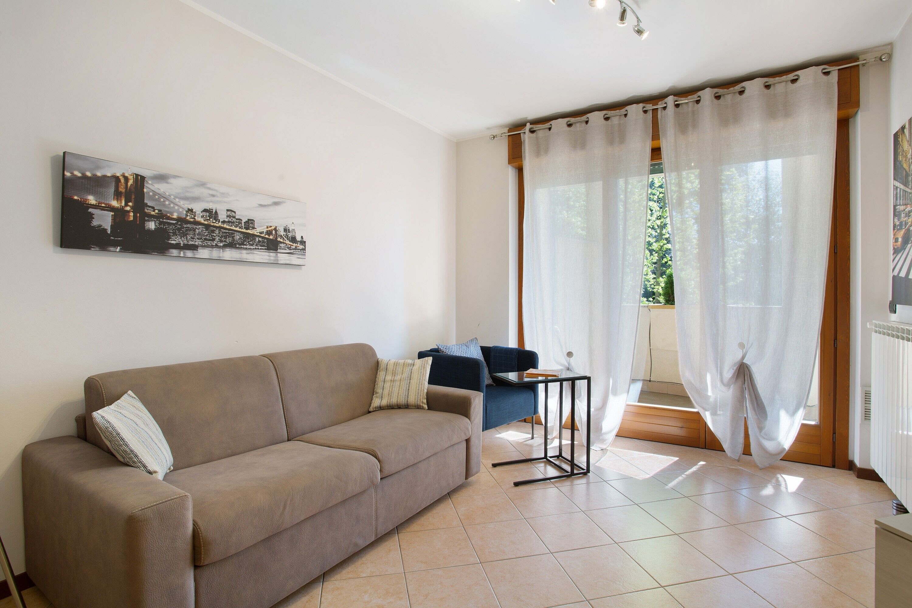 A living room with a sofa, a small table, and a window with curtains.