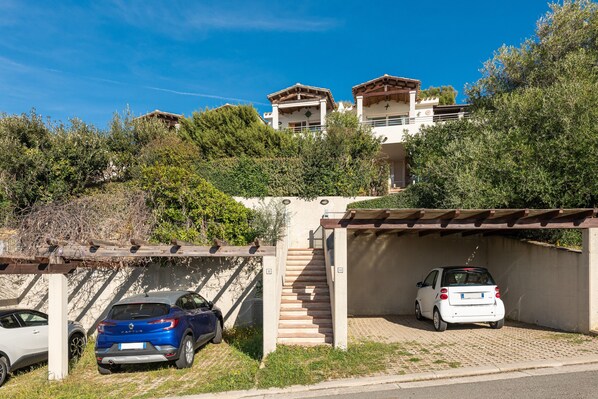A residential area with a staircase leading to a house, parked cars, and a pergola. - Holiday Home 'Casa Ricale' with Sea View, Wi-Fi and Air Conditioning (Quartu Sant'Elena)