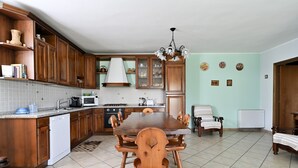 A kitchen with wooden cabinets, a dining table, and a chandelier. - Vacation Home "La Collina Degli Ulivi" with Sea View, Private Terrace & Wi-Fi (Bari Sardo)