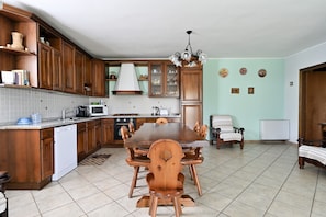 A kitchen with wooden cabinets, a dining table, and a chandelier.