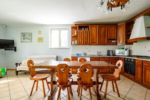 A kitchen with wooden cabinets, a dining table with chairs, a microwave, and a stove.