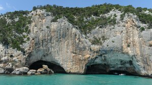 Eingang einer Küstenhöhle mit klarem, türkisblauem Wasser.