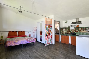 A bedroom with a bed, a bedside table, a hanging light fixture, and a view into the adjacent kitchen. - Studio Apartment "Naramanue 2" with Mountain View, Private Terrace & Wi-Fi (Dorgali)