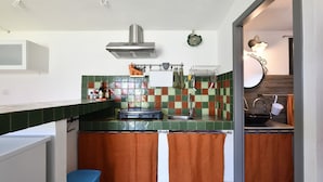Una cocina compacta con salpicadero de azulejos, una campana extractora de acero inoxidable y un lavamanos pequeño.