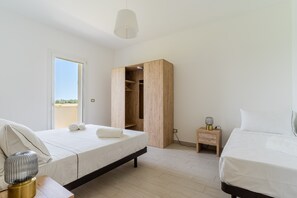 Ein Schlafzimmer mit Bett, Nachttisch, Lampe, Kleiderschrank und Blick durch die Tür.