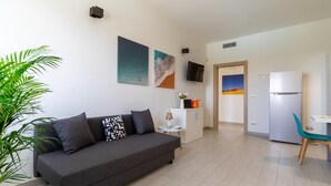 Ein modernes Wohnzimmer mit einer Couch, einem kleinen Tisch, einem Fernseher und einem Kühlschrank.