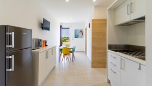 Una cocina moderna con electrodomésticos de acero inoxidable, un comedor con mesa y sillas, y vistas al exterior.