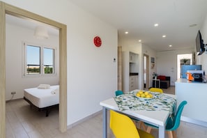 Un appartement moderne comprenant un coin repas, une cuisine et une chambre avec fenêtre.