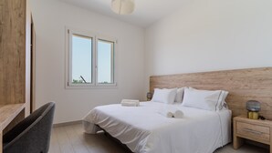 A bedroom with a bed, bedside table, lamp, chair, and window.