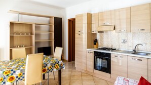 A modern kitchen with wooden cabinets, a built-in oven, and a dining area with a table and chairs.