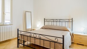 Um quarto com uma cama, mesas de cabeceira, um espelho e uma janela.