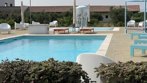 A swimming pool with lounge chairs and a water feature.