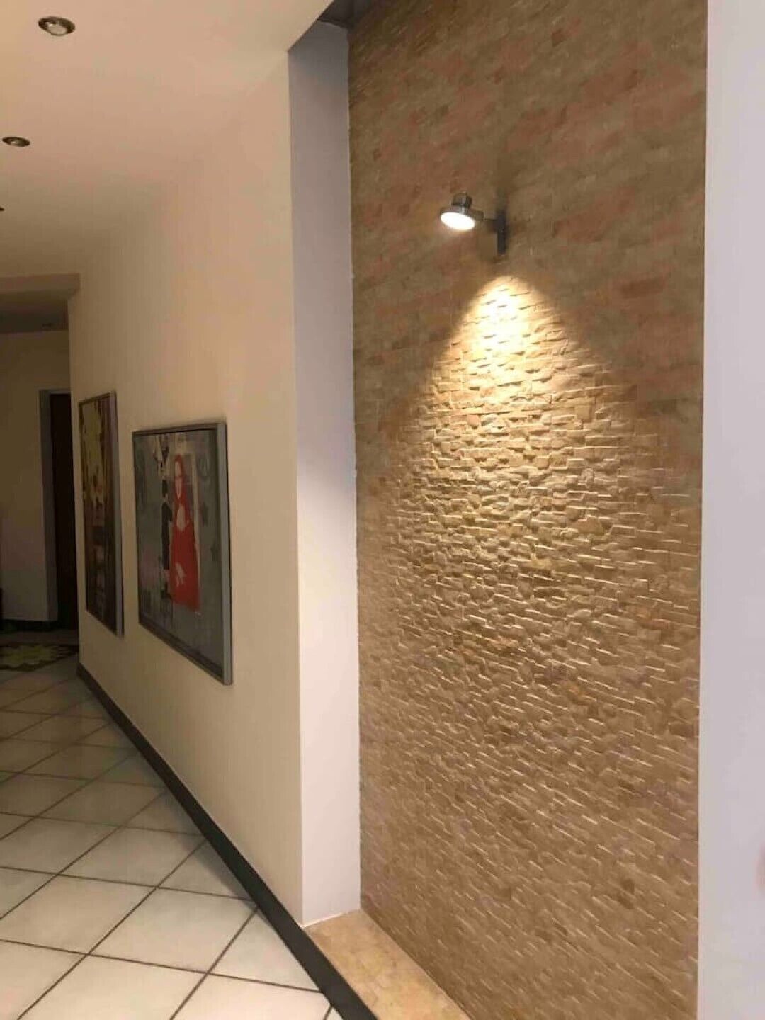 Un pasillo con piso de baldosas, pared de ladrillo decorativa e iluminación empotrada.