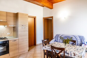 A kitchen with wooden cabinets, a stove, and a dining area with a table and chairs.