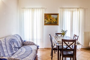 A dining area with a table and chairs, a painting on the wall, and a patterned sofa.