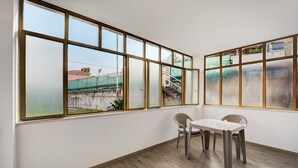 A room with large windows, a table with two chairs, and a wooden floor. - Holiday Home 'Il Gattino Di Porto Appartamento 3' with Shared Pool, Wi-Fi and Air Conditioning (Imperia)