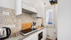 A modern kitchen with a built-in stove, oven, and a window with curtains. - Holiday Home 'Il Gattino Di Porto Appartamento 3' with Shared Pool, Wi-Fi and Air Conditioning (Imperia)