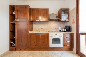 Una cucina con mobili in legno, forno integrato e macchina da caffè.