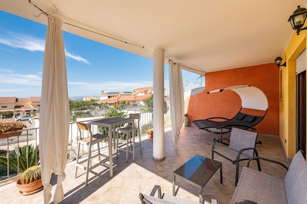 Un balcone con tavolo, sedie, barbecue e vista sugli edifici.