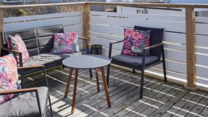 An outdoor deck with a wooden fence, two sofas with floral cushions, and a small round table. - 4 Star Holiday Home in Lysekil (Lysekil)