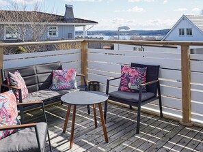 An outdoor deck with a wooden fence, two sofas with floral cushions, and a small round table.