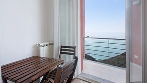 Un balcón con vista al mar, una mesa de madera y una silla.