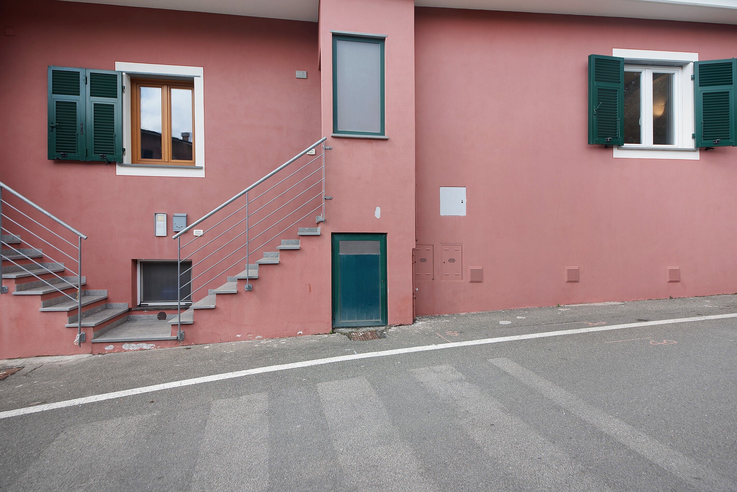Un edificio con fachada rosa, una escalera y una puerta.