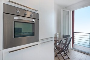 Eine moderne Küche mit Einbauofen, ein Essbereich mit Tisch und Stühlen sowie ein Balkon mit Blick.