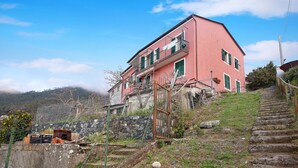 Un edificio rosa con balcón, escaleras de piedra y una valla.