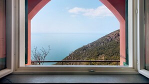 Una ventana con vistas a un paisaje costero, que incluye una masa de agua y una zona montañosa.