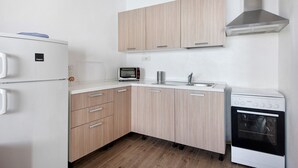 Cocina compacta con refrigerador, microondas, pileta y horno.