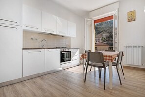 A kitchen with white cabinets, a stove, and a dining area with a table and chairs.
