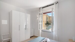 A bedroom with a bed, a wardrobe, a radiator, and a window with a view.