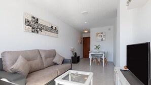 Un soggiorno moderno con un divano, un tavolino, una TV e opere d'arte alle pareti.
