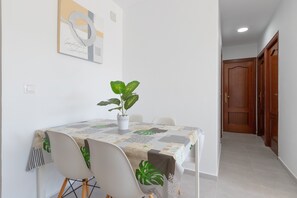 Un comedor con una mesa, sillas, una planta en maceta y una puerta al fondo.